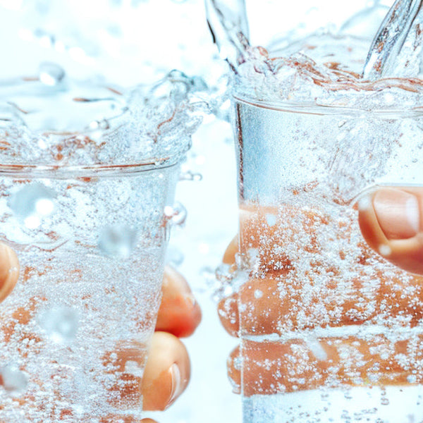 Two glasses of water clinking together