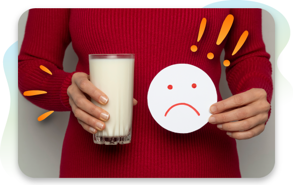 A woman holds a glass of milk in one hand and a paper cutout of a sad face in the other, visually representing the discomfort and negative symptoms associated with a dairy or lactose intolerance.