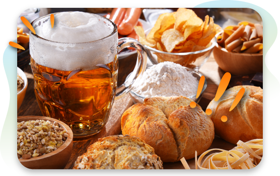 A mug of frothy beer is surrounded by a variety of common food intolerance triggers, including bread, pasta, chips, hot dogs, and a bowl of flour.