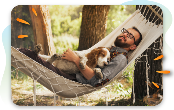 man cuddling dog in a hammock in the forest